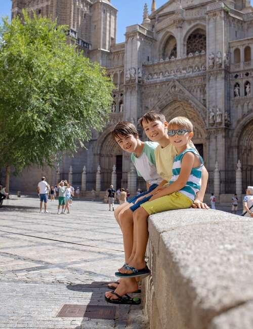 Child siblings sitting with each other in front of a monument in Portugal.