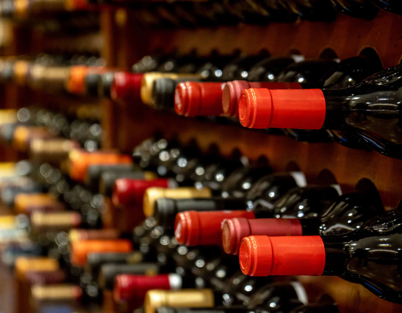 Bottles of black red wine lined up and stacked on wooden wine rack shelves from a private collection of a wine cellar in Spain.