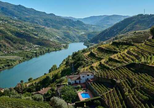 Two young women sit at the table and relax, observing the beautiful view on the bank of the Douro River in Pinhao, Portugal.