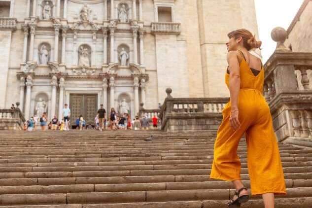 youngss Young tourist wearing orange posing at Girona Cathedral in the medieval city of Girona, Catalonia, along Spain’s Costa Brava in the Mediterranean.